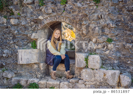Young tourist woman enjoying a view of Kotor Bay, Montenegro. Kotor Old Town Ladder of Kotor Fortress Hiking Trail. Aerial drone view 86531897