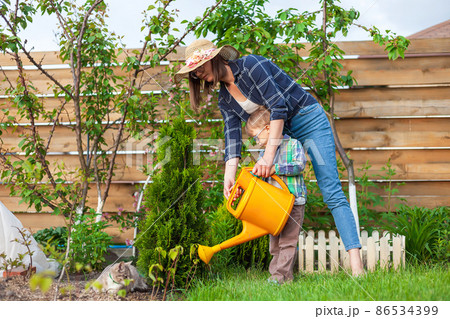 Child and mother watering can watering a garden in the backyard 86534399