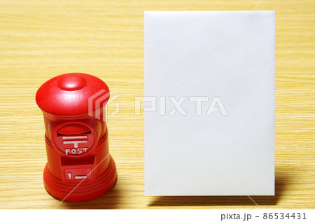 木目の机に置いた郵便ポスト形の貯金箱と郵便封筒(コピースペース有り) 木目の机に置いた郵便ポスト形の貯金箱と郵便封筒(コピースペース有り) 86534431