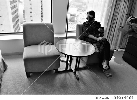 ホテル高層階の部屋に入ってソファに座り、くつろぐ女性 86534434
