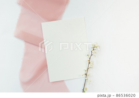 Spring wedding or birthday mock up scene. Blank open sheet of paper and branch with place for text for greeting card copyspace. Valentines card on pink and white background. Flat lay, top view Spring wedding or birthday mock up scene. Blank open sheet of paper and branch with place for text for greeting card copyspace. Valentines card on pink and white background. Flat lay, top view 86536020