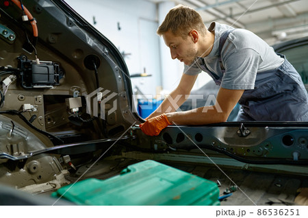 Workman fixing bolt during car body repair 86536251