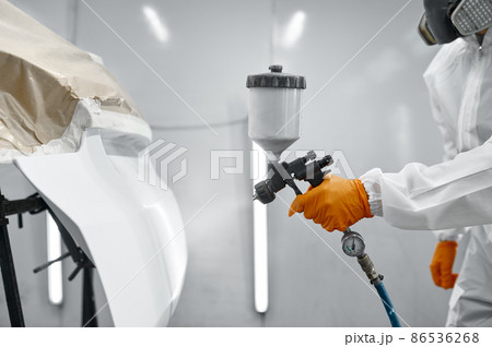 Technician in safety clothing spraying car paint Technician in safety clothing spraying car paint 86536268