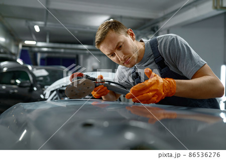Man using grinder to remove car rust 86536276