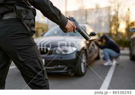 Policewoman holding gun at car thief backview 86536293