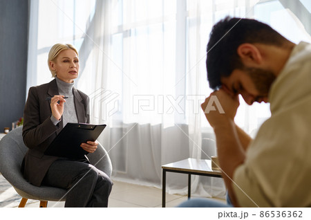 Psychologist talking to depressed frustrated unhappy man 86536362