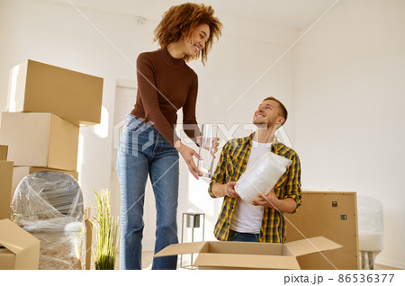 Couple packing stuff among plenty of boxes Couple packing stuff among plenty of boxes 86536377