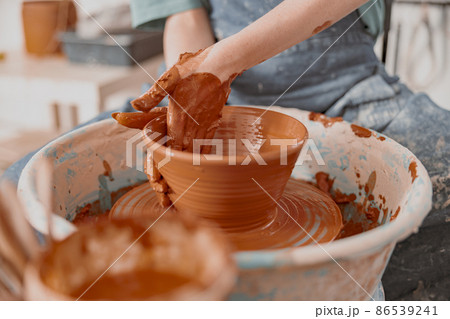 Skillful female potter creating earthen bowl on circle in workroom Skillful female potter creating earthen bowl on circle in workroom 86539241