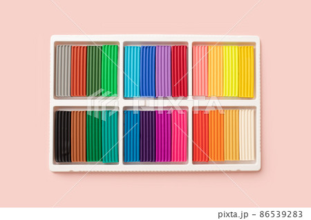 24 colors set of colorful plasticine sticks in white plastic packaging isolated on pink background. Pieces of multicolor plasticine modeling clay. Top view, closeup. 24 colors set of colorful plasticine sticks in white plastic packaging isolated on pink background. Pieces of multicolor plasticine modeling clay. Top view, closeup. 86539283