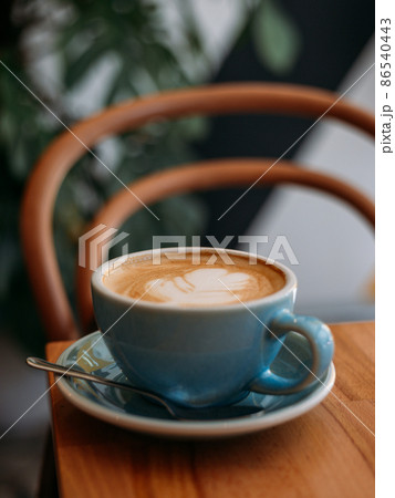 One Cup of cappuccino with latte art. Coffee in blue cup on wooden table in cafe. Concept of easy breakfast. One Cup of cappuccino with latte art. Coffee in blue cup on wooden table in cafe. Concept of easy breakfast. 86540443