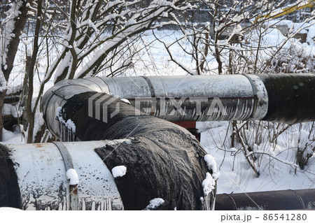 The main provides the city with hot water. Selective focus. The large pipes of the central heating system are covered with snow. Icicles on pipes. fuel crisis. Increasing the cost of heating. The main provides the city with hot water. Selective focus. The large pipes of the central heating system are covered with snow. Icicles on pipes. fuel crisis. Increasing the cost of heating. 86541280