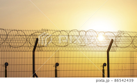 Barbed wire wall against the backdrop of the setting sun Barbed wire wall against the backdrop of the setting sun 86542439