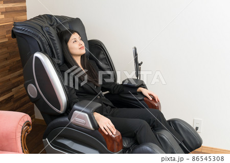 マッサージチェアに座ってマッサージしている若い女性 86545308