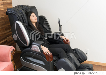 マッサージチェアに座ってマッサージしている若い女性 マッサージチェアに座ってマッサージしている若い女性 86545309