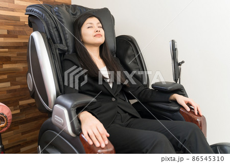 マッサージチェアに座ってマッサージしている若い女性 マッサージチェアに座ってマッサージしている若い女性 86545310