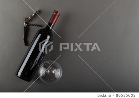 Corked red wine bottle, corkscrew and empty wine glass on gray background Corked red wine bottle, corkscrew and empty wine glass on gray background 86555605