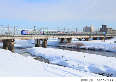 雪晴れの豊平川橋梁を通過して終着札幌駅にまもなく滑り込む特急「おおぞら」 86557433