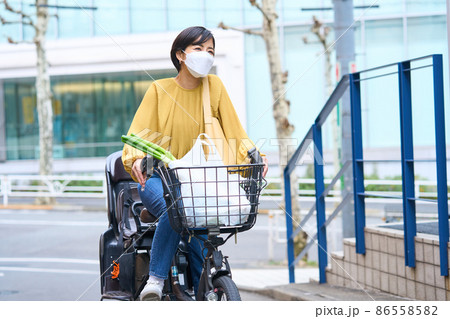 自転車に乗ってスーパーで買い出しをするマスク姿のママ 自転車に乗ってスーパーで買い出しをするマスク姿のママ 86558582