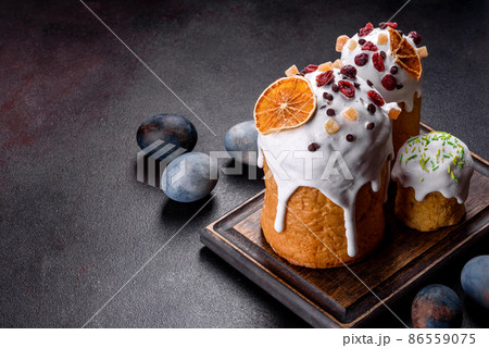 Festive cakes with white glaze, nuts and raisins with Easter eggs on the festive table 86559075