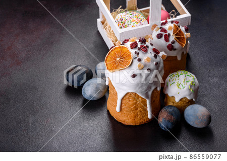 Festive cakes with white glaze, nuts and raisins with Easter eggs on the festive table 86559077