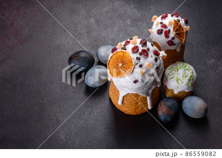 Festive cakes with white glaze, nuts and raisins with Easter eggs on the festive table 86559082