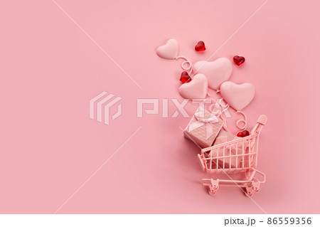 Heart shaped baloons in the pink shopping cart on a pink background. Season sale, spring shoping concept. Valentines day. 86559356