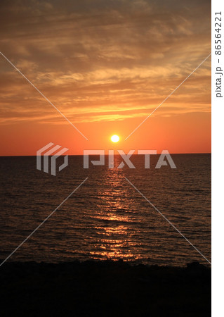 オレンジ色の太陽に照らされた夕方の海の風景写真 86564221
