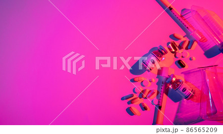 Covid-19 medication. Neon banner. Pharmaceutical manufacture. Color light vaccine bottle dose syringe pills test tube composition on bright pink purple copy space background. 86565209