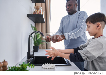 Multiracial father and caucasian son washing hands in kitchen 86565672