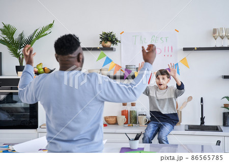 Father looking at each other and rejoicing while standing at the kitchen and celebrating Fathers Day 86565785