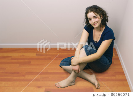 young girl brunette sitting onrange wooden floor barefoot 86566071