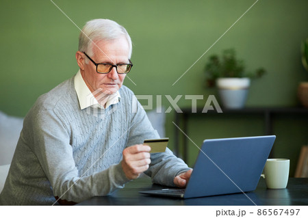 Modern senior man entering number of credit card during online payment Modern senior man entering number of credit card during online payment 86567497