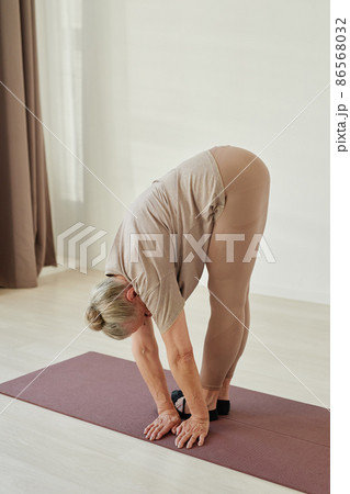 Aged retired woman in sports clothes bending forwards and turning aside Aged retired woman in sports clothes bending forwards and turning aside 86568032