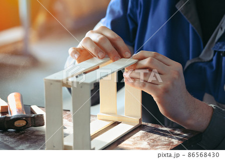 Young Caucasian carpenter in working clothes makes wooden boxes in carpentry workshop. Real scene 86568430