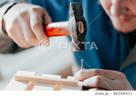 Young Caucasian carpenter in working clothes makes wooden boxes in carpentry workshop. Hands with Young Caucasian carpenter in working clothes makes wooden boxes in carpentry workshop. Hands with 86568431