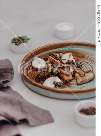 Fillet of beef with mushroom sauce on a light background. Microgreens in small gravy boat Fillet of beef with mushroom sauce on a light background. Microgreens in small gravy boat 86568845