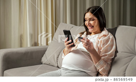 Brunette pregnant woman pays for online shopping via phone Brunette pregnant woman pays for online shopping via phone 86569549