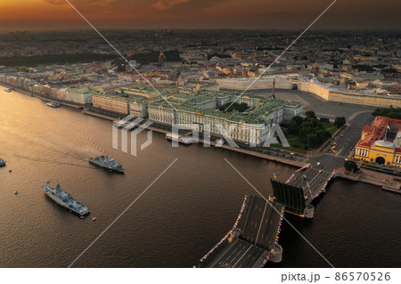 Aerial landscape with warships in the Neva River before the holiday of the Russian Navy at early morning, warships pass under a raised drawbridge, the latest cruisers among landmarks, Palace bridge Aerial landscape with warships in the Neva River before the holiday of the Russian Navy at early morning, warships pass under a raised drawbridge, the latest cruisers among landmarks, Palace bridge 86570526