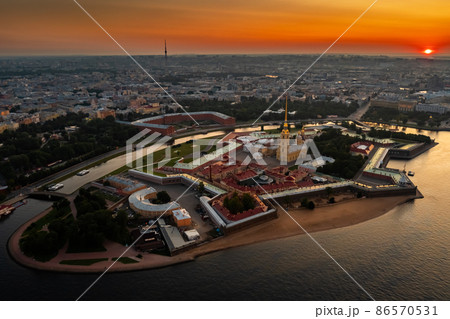 The Peter and Paul Fortress at sunrise, reflection of the orange and pink sky on the water, drawbridges Troitsky and Liteiny are separated 86570531
