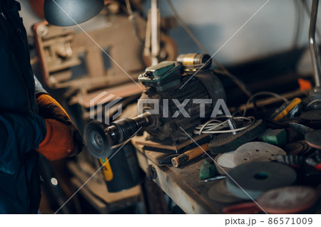 Blacksmith forges and cleaning arrow metal detail with hammer and anvil at forge. 86571009
