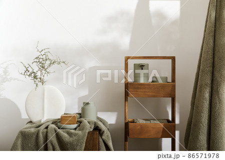 Modern aesthetic bathroom accessories in eucalyptus light green shade. Organic cotton bath towels, minimalistic Scandinavian style vase, sensor soap and lotion dispenser on solid oak stump. Daily Modern aesthetic bathroom accessories in eucalyptus light green shade. Organic cotton bath towels, minimalistic Scandinavian style vase, sensor soap and lotion dispenser on solid oak stump. Daily 86571978
