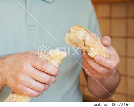 Man breaks off hunk of fresh baked homemade crusty bread baguette. Delicious Man breaks off hunk of fresh baked homemade crusty bread baguette. Delicious 86572166