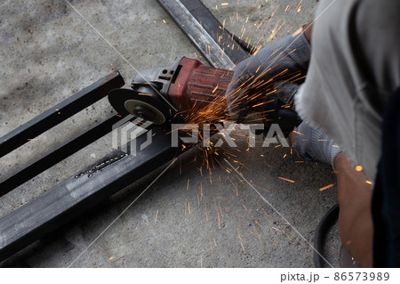 Close up, A man working with angle grinder. Iron gate repair 86573989
