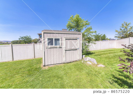 Backyard shed with window near the large rocks and trees on a green lawn Backyard shed with window near the large rocks and trees on a green lawn 86575220