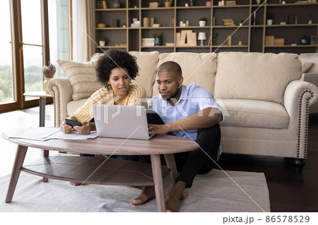 Serious African couple paying bills online, calculate expenses at home Serious African couple paying bills online, calculate expenses at home 86578529