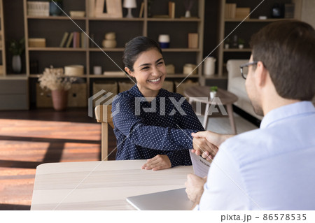 Smiling young Indian woman shaking hands with hr manager. 86578535