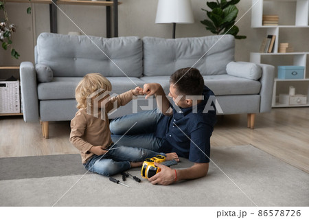 Happy cute small son bumping fists with caring millennial father. 86578726