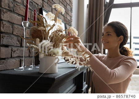 Young Latin female homeowner improving dwelling view with dried flowers Young Latin female homeowner improving dwelling view with dried flowers 86578740
