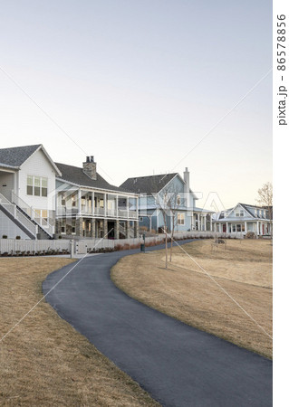 Paved curved sidewalk path along the row of large houses Paved curved sidewalk path along the row of large houses 86578856