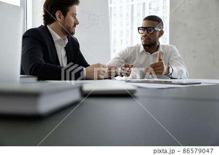 Diverse business partners discussing project at meeting table Diverse business partners discussing project at meeting table 86579047